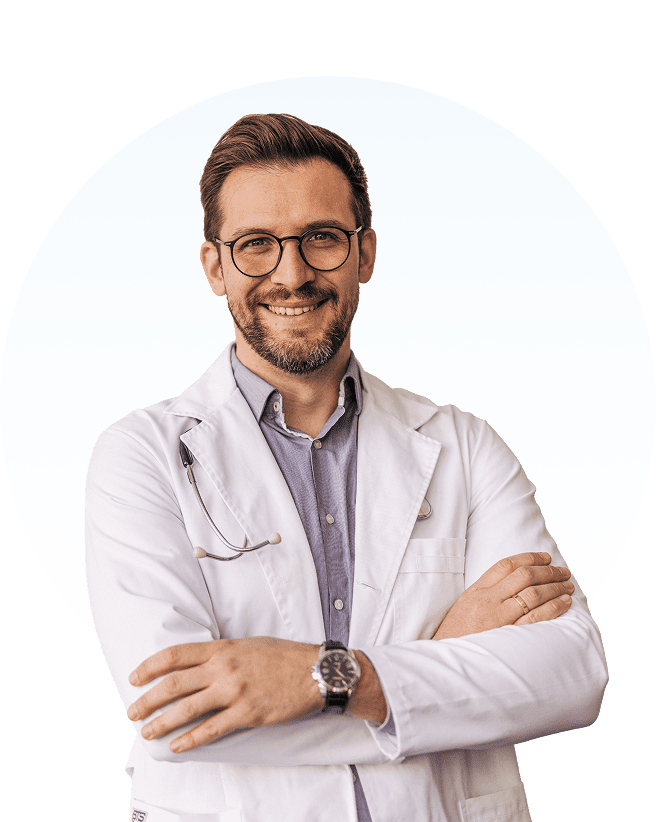 Smiling male doctor with glasses and crossed arms.