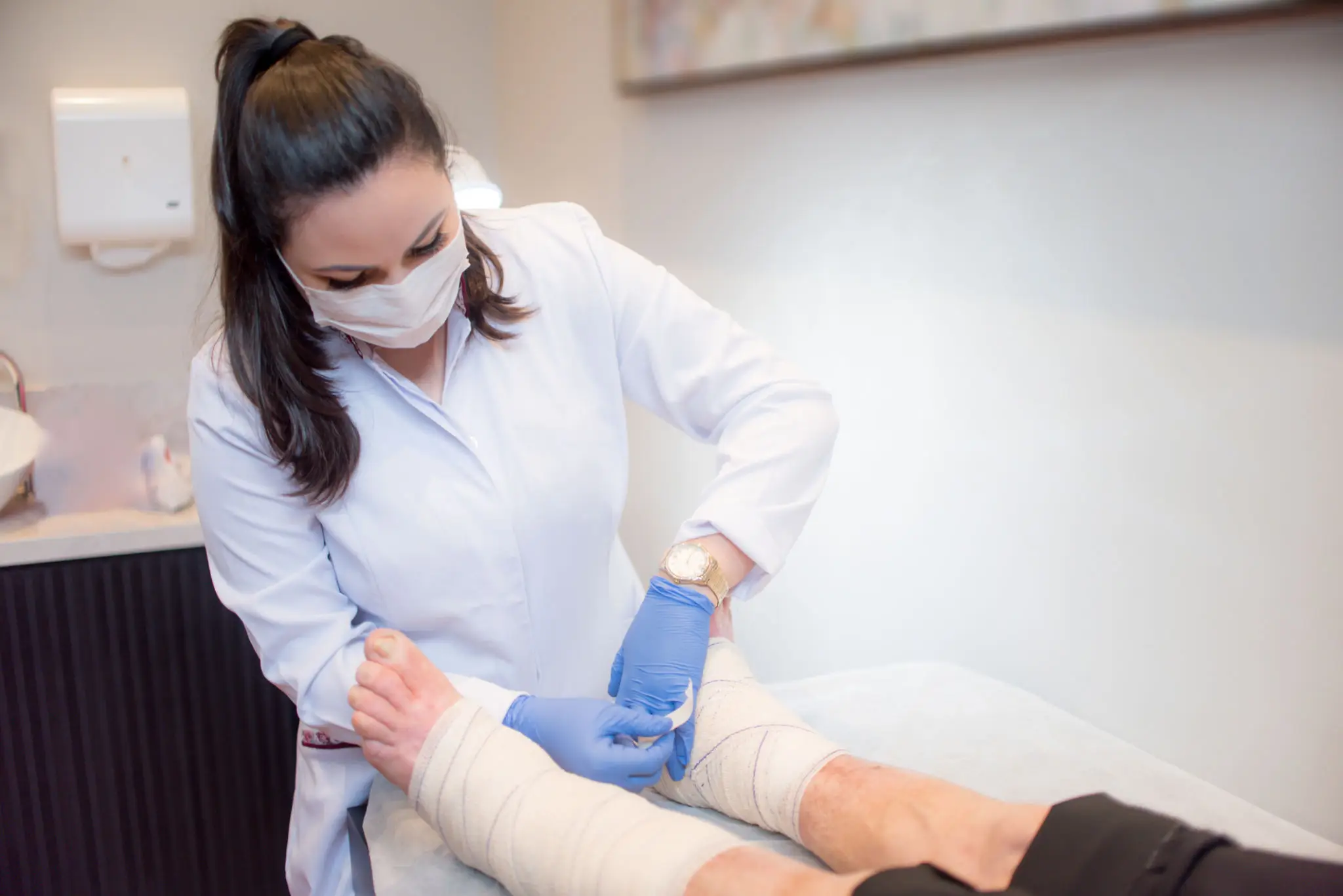 A healthcare professional performs a medical procedure on a patient's foot.